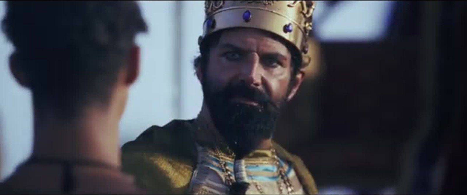 A bearded king in a gold crown set with blue stones, wearing embroidered robes, faces another man in Daniel and the Fiery Furnace