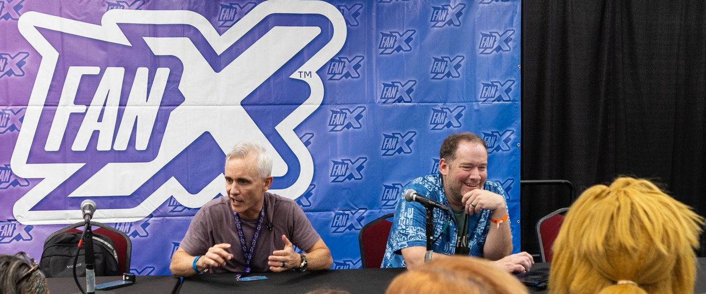 Director Cameron Sawyer gestures while speaking beside author Brandon Mull at a FanX panel table in Salt Lake City